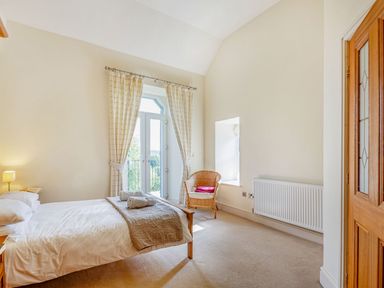 A bedroom with a single bed towels on the bed a wicker chair by the window and curtains at Menai View Llanfairpwllgwyngyll near Beaumaris