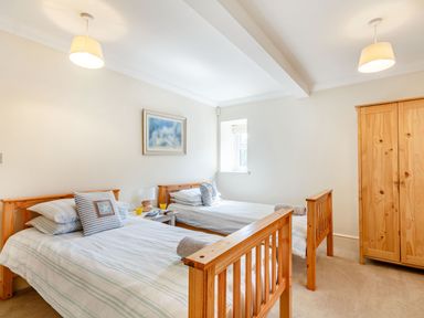 A bedroom with two wooden single beds a wooden wardrobe a small bedside table with two glasses and a lamp and a framed picture on the wall at Menai View in Llanfairpwllgwyngyll near Beaumaris