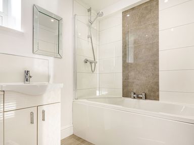 A bathroom with a bathtub and shower head a sink with cabinet and a mirror at Menai View in Llanfairpwllgwyngyll near Beaumaris