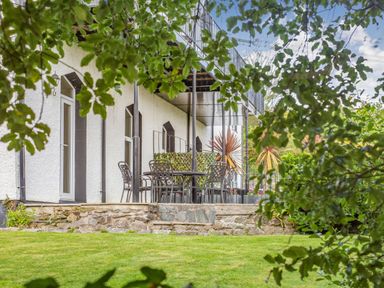 An outdoor patio with metal chairs and a table surrounded by greenery at Menai View in Llanfairpwllgwyngyll near Beaumaris