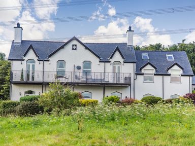 Exterior view of a two-story house with a balcony and garden at Menai View in Llanfairpwllgwyngyll near Beaumaris