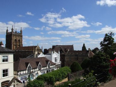 A view of historic buildings and a church tower under a partly cloudy sky in Beckford near Tewkesbury