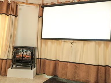 A stove heater next to a projection screen with curtains in the background at Island Yurt in Beckford near Tewkesbury