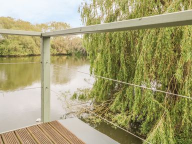 A wooden deck with railing overlooking a river with trees at Island Yurt Beckford near Tewkesbury