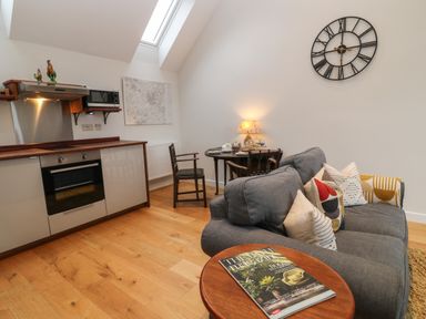 A small kitchen and dining area with a grey sofa and a round table with chairs at The Loft at Lucott House in Bath