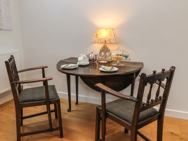 A small dining area with a round wooden table and two wooden chairs with cushions at The Loft at Lucott House in Bath