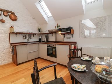 A kitchen with wooden countertops and shelves with copper pans on the wall a round dining table with plates and scones at The Loft at Lucott House in Bath