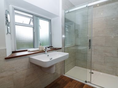 A bathroom with a wall-mounted sink and a glass-enclosed shower at The Loft at Lucott House in Bath