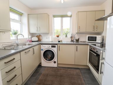 A kitchen with cabinets a washing machine a microwave an oven a sink and utensils at The Old Stable in Mold