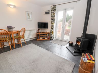 A living room with a wood burning stove table with chairs and a television at The Old Stable in Mold