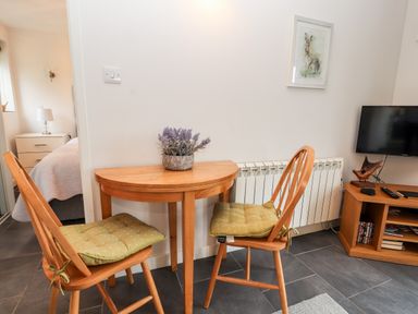 A small dining area with two wooden chairs and a wooden table with a plant in a pot at The Old Stable in Mold
