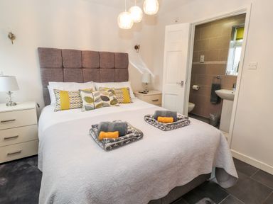 A bedroom with a double bed, bedside tables with lamps, and an ensuite bathroom at The Old Stable in Mold