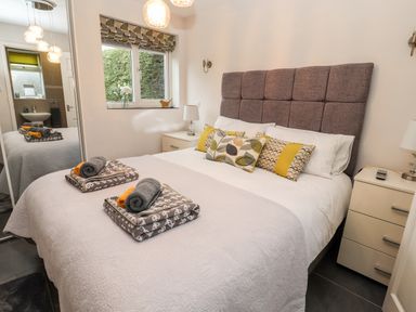 A bedroom with a bed with gray headboard and folded towels on the bed at The Old Stable in Mold