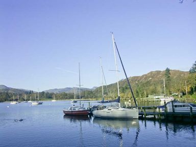Boats docked at a wooden pier on a lake with hills in the background at High View Lodge in White Cross Bay near Troutbeck Bridge
