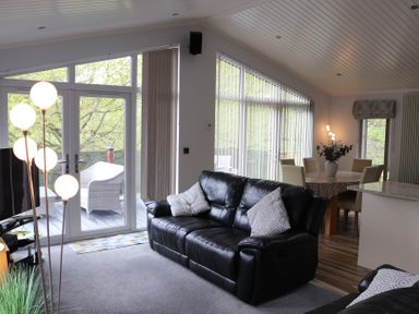 A living room with a sofa and a dining table at High View Lodge White Cross Bay near Troutbeck Bridge