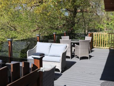 A deck with outdoor seating and a table at High View Lodge in White Cross Bay near Troutbeck Bridge