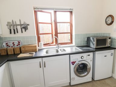 A kitchen counter with a sink washing machine microwave and knives on a magnetic strip at The Old Dairy in Newnham-on-Severn