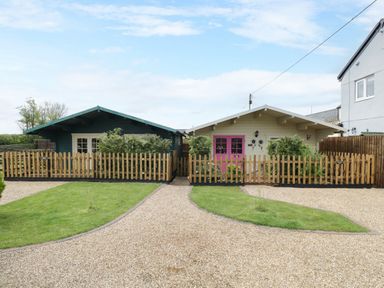 Two small houses with fenced front yards and gravel driveways