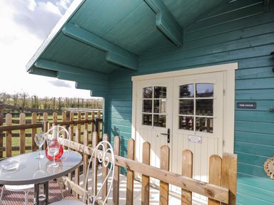 A small fenced porch with a round table and two chairs outside double cream doors at The Nook Royal Wootton Bassett