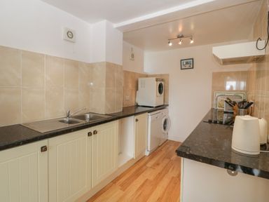 A kitchen with a sink dishwasher washing machine microwave electric kettle and stove at Wheelbarrow Cottage Stoke Prior near Leominster