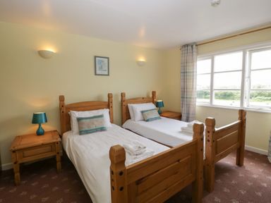 A bedroom with two single wooden beds beside a window at Wheelbarrow Cottage Stoke Prior near Leominster