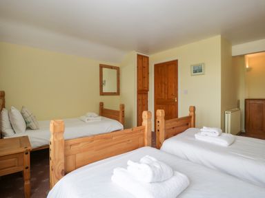 A bedroom with three single wooden beds with white linens and towels at Wheelbarrow Cottage in Stoke Prior near Leominster