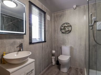 A bathroom with a sink cabinet mirror window toilet and shower at Stone Water Cottage in Strathpeffer