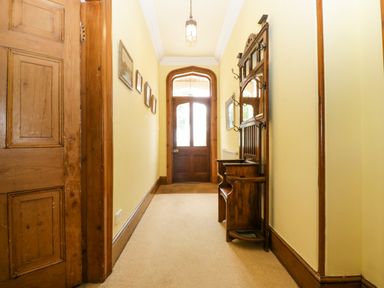 A hallway with wooden door wooden coat rack and framed pictures on yellow walls at Wheelbarrow Castle in Leominster