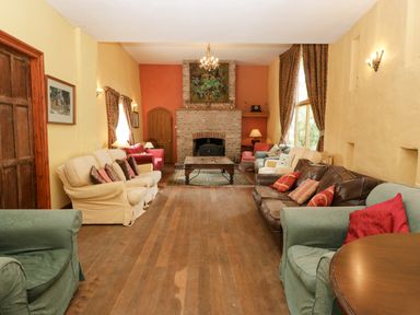 A living room with multiple sofas and armchairs around a wooden coffee table and a fireplace at Wheelbarrow Castle in Leominster