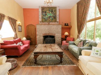 A living room with a wooden coffee table and sofas around a fireplace at Wheelbarrow Castle in Leominster