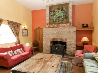 A living room with a wooden coffee table a stone fireplace and colorful sofas at Wheelbarrow Castle in Leominster