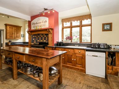 A kitchen with wooden cabinets a large wooden island and a window above the sink at Wheelbarrow Castle in Leominster