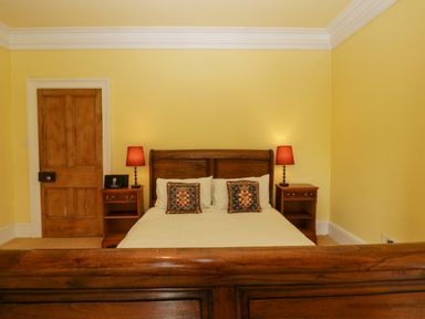 A bedroom with a wooden bed frame two bedside tables with lamps and a wooden door at Wheelbarrow Castle in Leominster