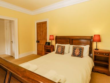A bedroom with a wooden bed, two nightstands with lamps, and a wooden door at Wheelbarrow Castle in Leominster