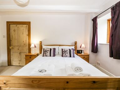 A bedroom with a wooden bed white bedding and rolled towels on the bed at Wheelbarrow Castle in Leominster