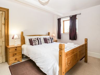 A bedroom with a wooden double bed bedside tables lamps and a window with curtains at Wheelbarrow Castle in Leominster