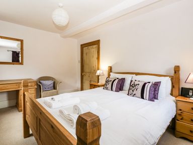 A bedroom with a wooden bed, bedside tables with lamps, a wooden desk, a chair, and a mirror at Wheelbarrow Castle in Leominster