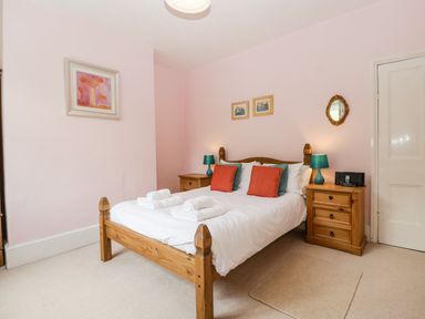 A bedroom with a wooden bed and two wooden bedside tables with lamps at Wheelbarrow Castle in Leominster
