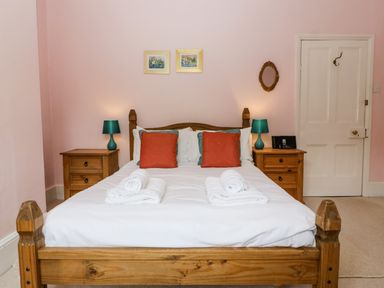 A bedroom with a wooden bed two bedside tables with lamps towels on bed and pictures on wall at Wheelbarrow Castle in Leominster
