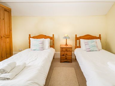 A bedroom with two single beds separated by a wooden nightstand with a lamp at Wheelbarrow Castle in Leominster