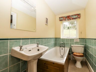 A bathroom with a sink a bathtub and a toilet below a window at Wheelbarrow Castle in Leominster