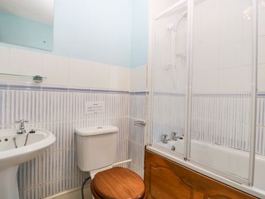 A bathroom with a sink toilet with wooden seat and bathtub with shower screens at Wheelbarrow Castle in Leominster