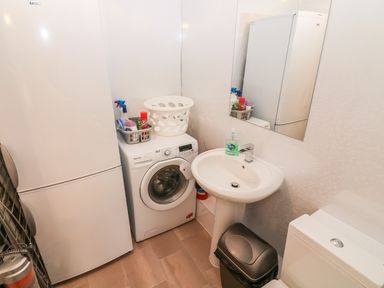 A laundry room with washing machine refrigerator sink mirror and trash bin at Sandown in Bowness-on-Windermere