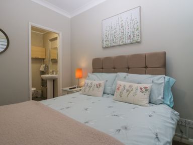 A bedroom with a bed and a bedside table with a lamp and an en suite bathroom at Sandown in Bowness-on-Windermere