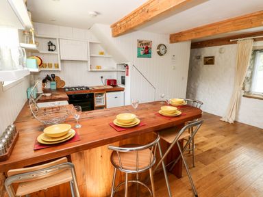 A kitchen with wooden countertops a wooden dining table set with yellow dishes and metal chairs at Beekeeper's Cottage in Pembroke