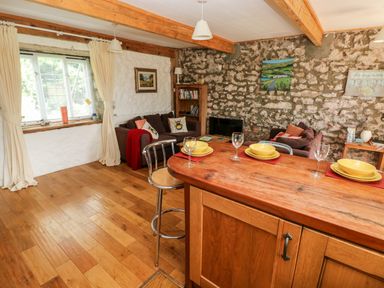 A living room with wooden floors sofas and a wooden dining table set with dishes at Beekeeper's Cottage in Pembroke