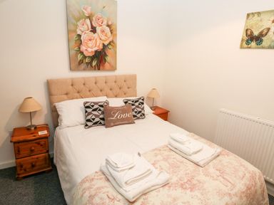 A bedroom with a bed with pillows and folded towels and bedside tables with lamps at Beekeeper's Cottage in Pembroke
