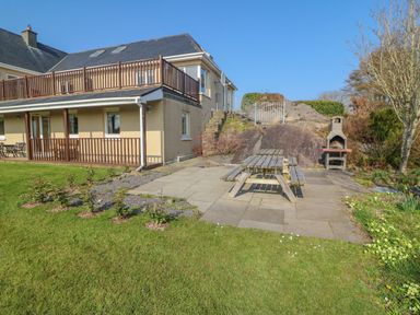 A house with a patio table and benches on a paved area next to a barbecue grill in a garden at Bluebell House and Gardens in Gurteenulla near Ballydehob County Cork