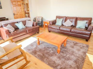 A living room with two brown leather sofas a wooden coffee table and a wooden rocking chair at Bluebell House and Gardens Gurteenulla near Ballydehob County Cork