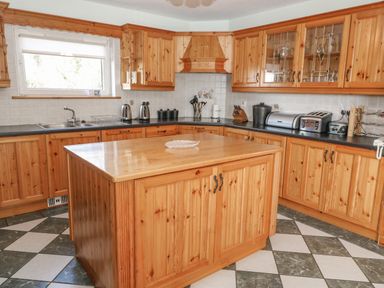 A kitchen with wooden cabinets a central wooden island a window two toasters and a dish drying rack at Bluebell House and Gardens Gurteenulla near Ballydehob County Cork